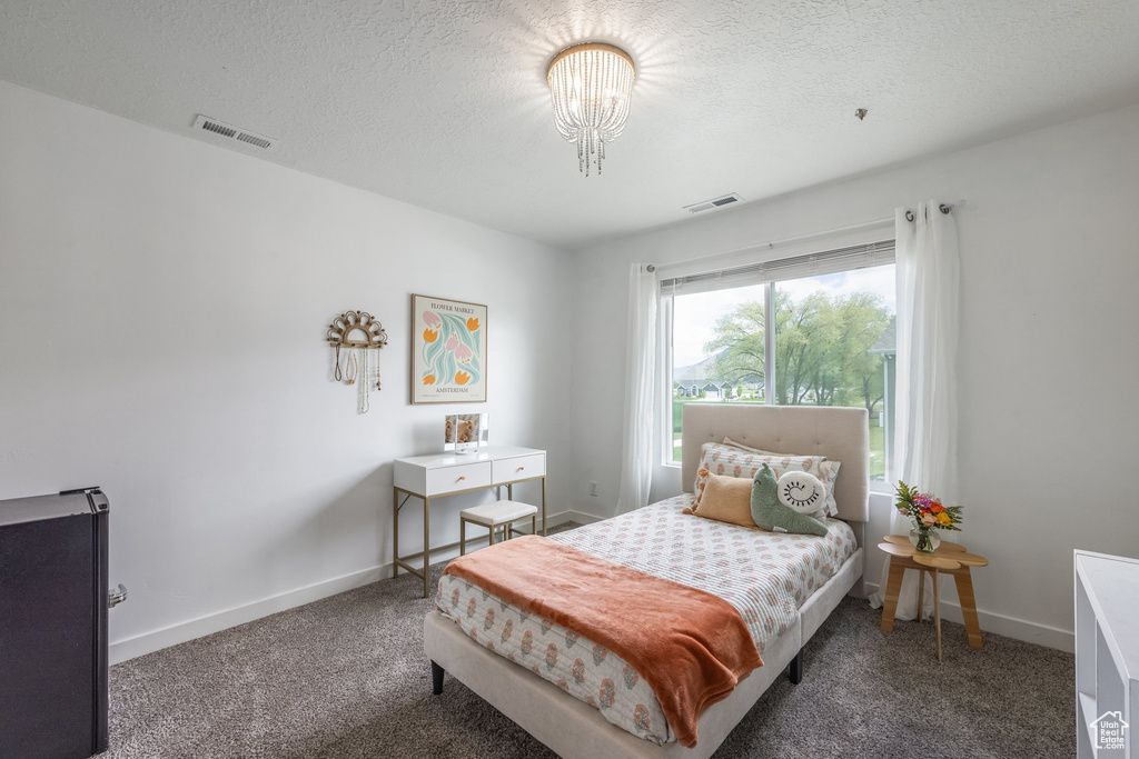 Carpeted bedroom with visible vents, a textured ceiling, and baseboards