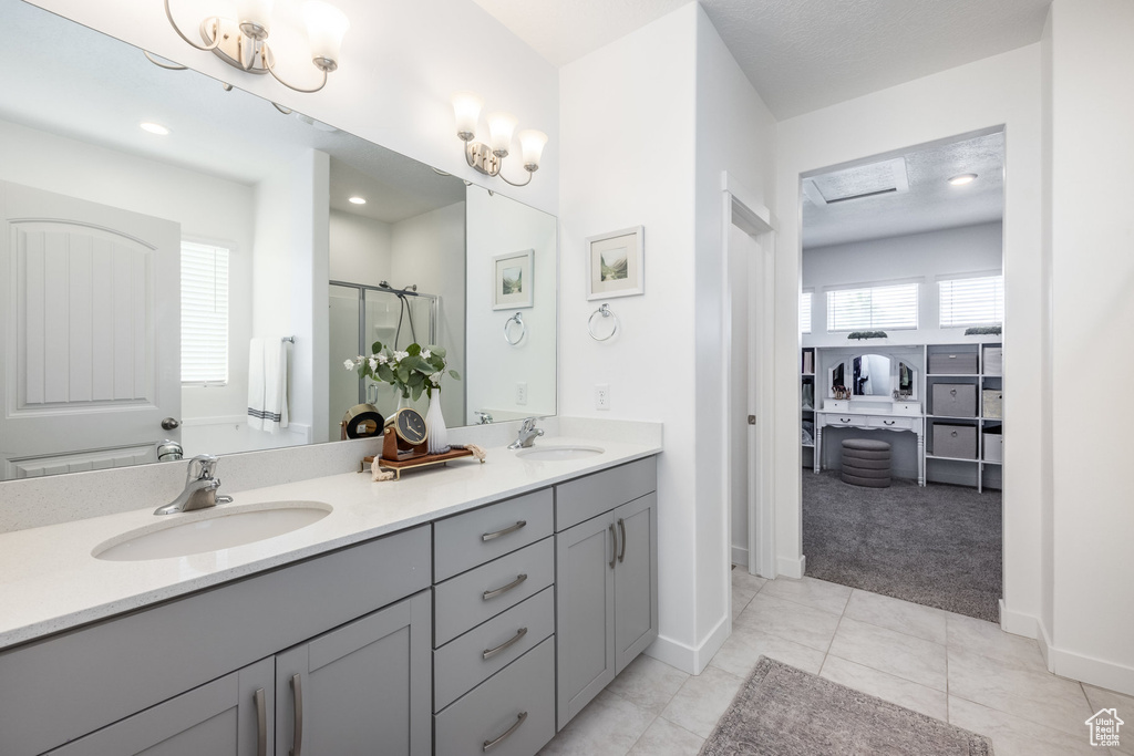 Bathroom with a sink, baseboards, a shower stall, and double vanity