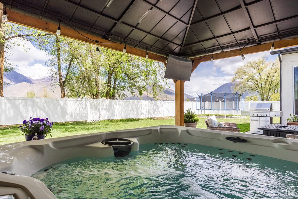 View of pool featuring a trampoline, a gazebo, fence, a mountain view, and a grill