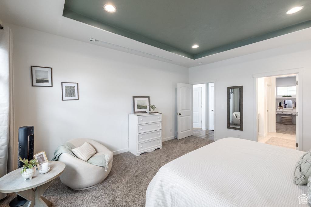 Bedroom featuring baseboards, recessed lighting, light colored carpet, a raised ceiling, and ensuite bath