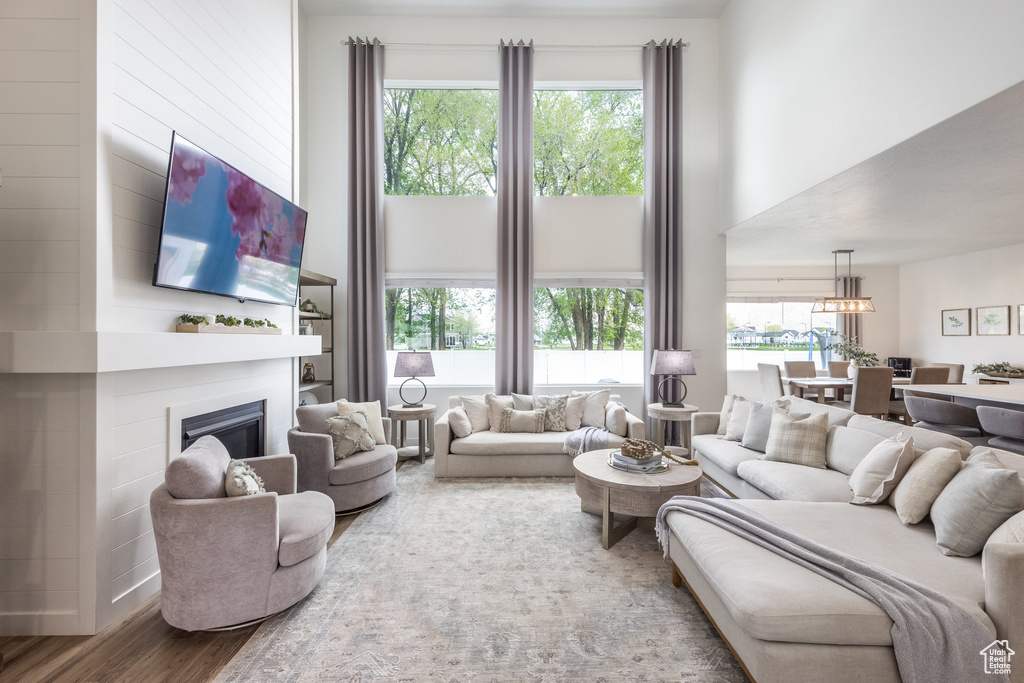 Living room featuring plenty of natural light, a glass covered fireplace, wood finished floors, and a notable chandelier