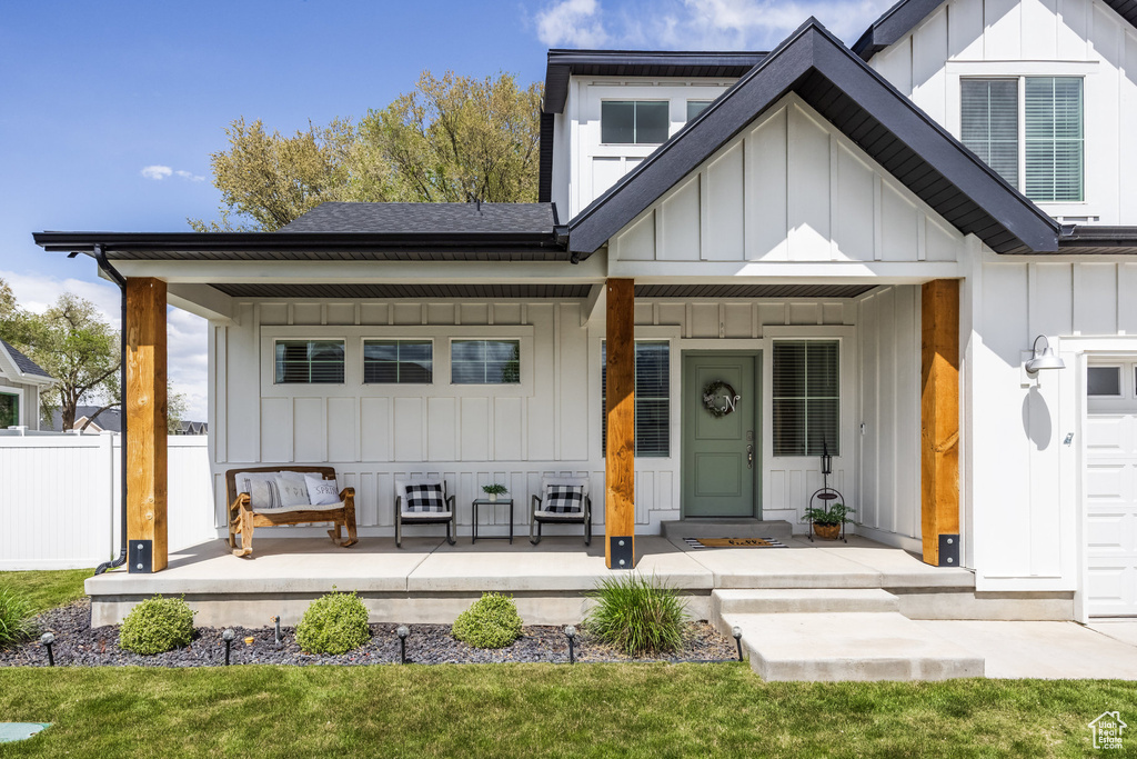 View of front of house with a porch, fence, board and batten siding, and a shingled roof