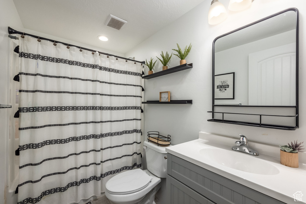 Full bath with visible vents, curtained shower, vanity, toilet, and recessed lighting