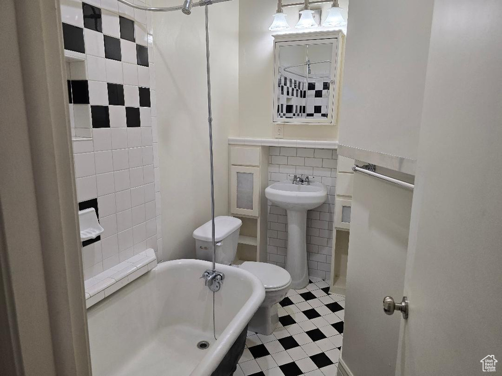 Full bathroom featuring a sink, a tub, toilet, and tile walls