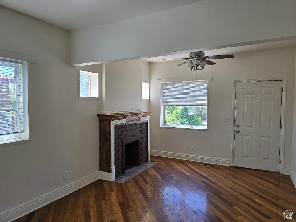 Unfurnished living room with baseboards, a fireplace, a wealth of natural light, and hardwood / wood-style flooring