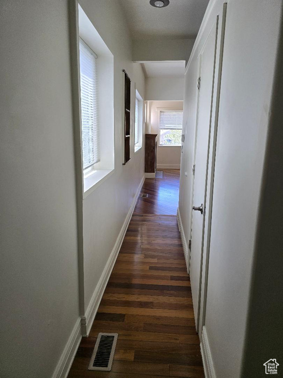 Hallway with visible vents, baseboards, and dark wood-type flooring