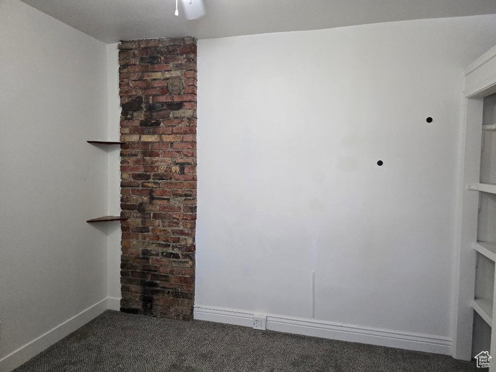 Unfurnished room featuring dark colored carpet, a ceiling fan, and baseboards