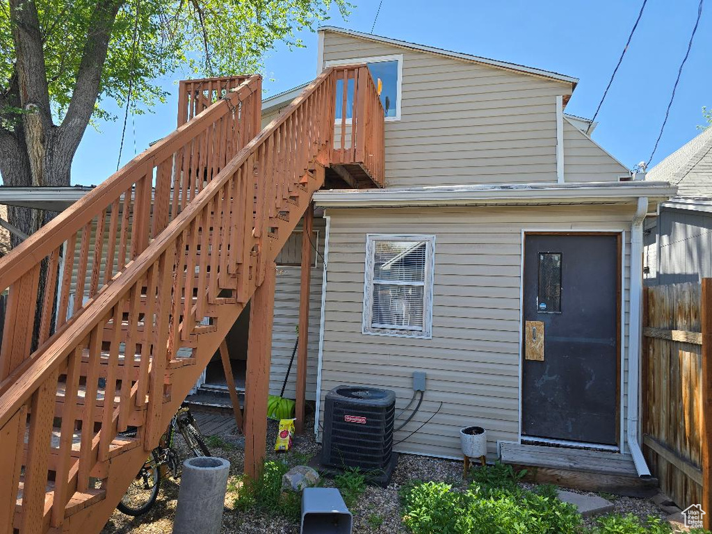 Back of property featuring stairs, central AC, a deck, and fence