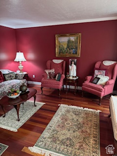 Living area with baseboards, crown molding, and wood finished floors