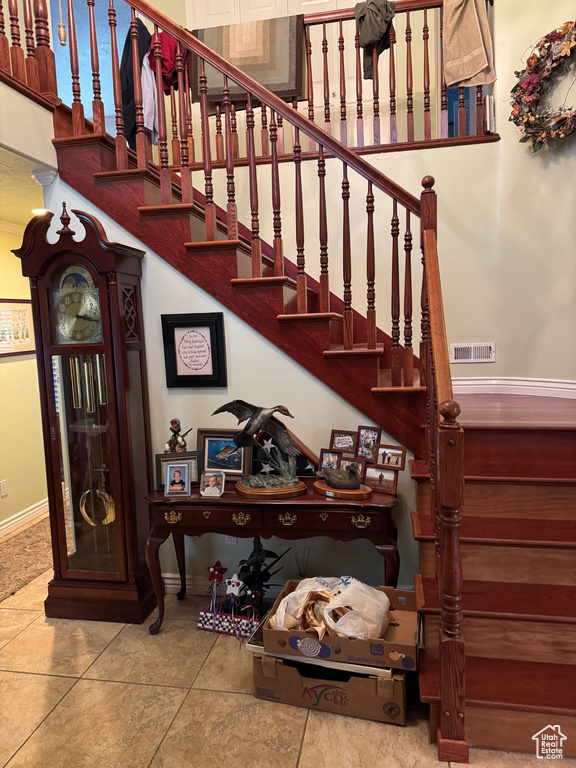 Stairs with tile patterned floors, visible vents, and baseboards