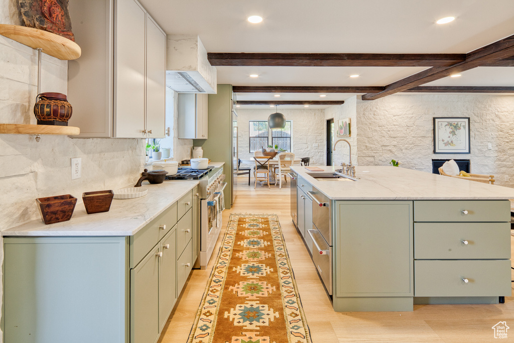 Kitchen featuring high end stove, open shelves, a sink, and green cabinets