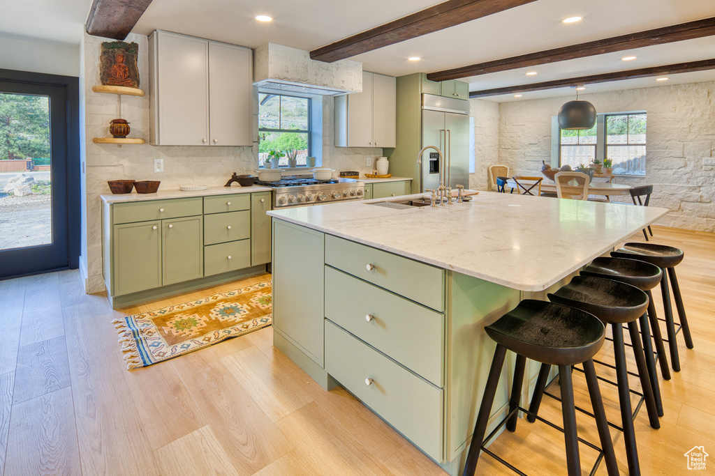 Kitchen with open shelves, beamed ceiling, light wood-style flooring, green cabinets, and stainless steel built in refrigerator