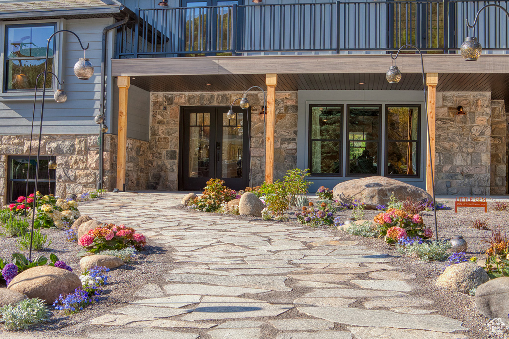 Doorway to property featuring french doors, a balcony, and stone siding