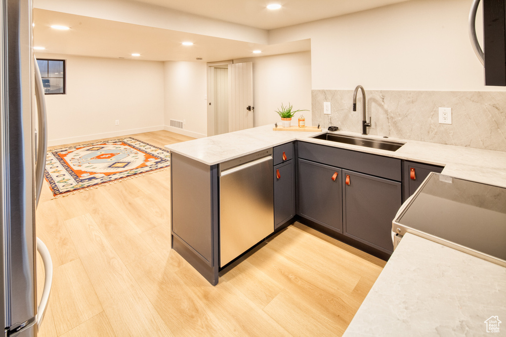 Kitchen featuring light wood-type flooring, a sink, a peninsula, stainless steel appliances, and recessed lighting