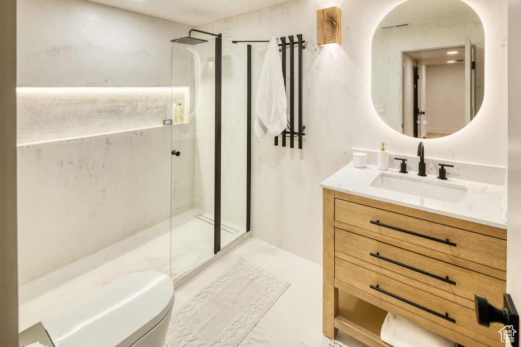 Bathroom with a marble finish shower, vanity, and toilet