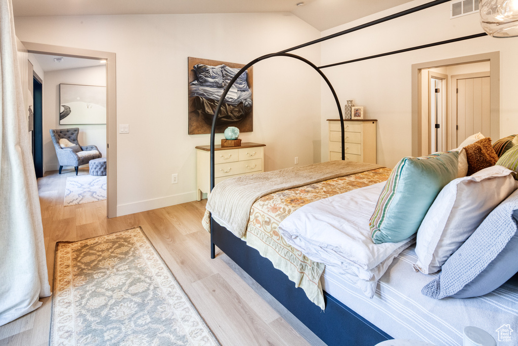 Bedroom featuring baseboards, vaulted ceiling, wood finished floors, and visible vents