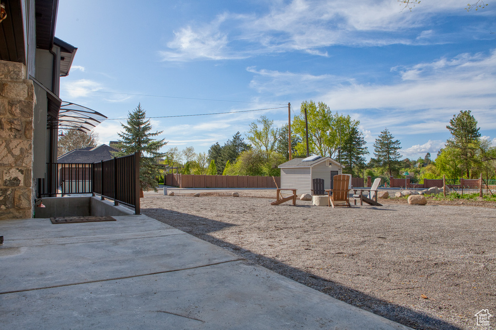 View of yard with a storage shed, fence, an outdoor structure, and a patio area