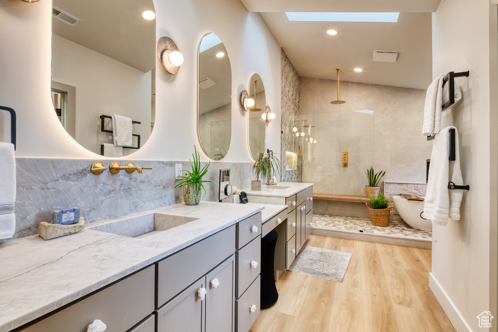 Bathroom featuring visible vents, a skylight, wood finished floors, vanity, and a walk in shower