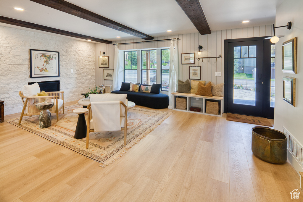 Living area with a fireplace, beam ceiling, wood finished floors, and visible vents