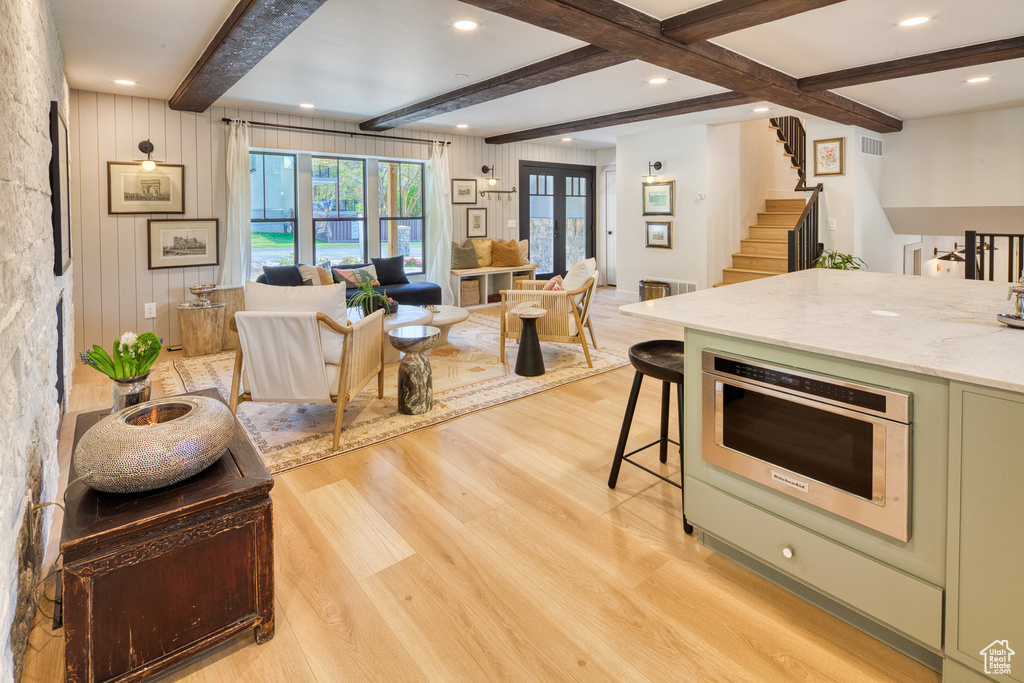 Kitchen featuring beamed ceiling, green cabinets, light wood finished floors, and open floor plan