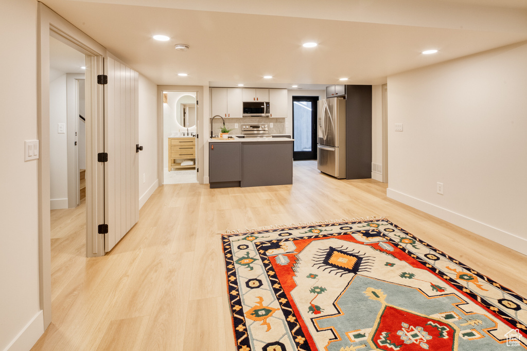 Kitchen with light countertops, baseboards, light wood finished floors, stainless steel appliances, and white cabinetry