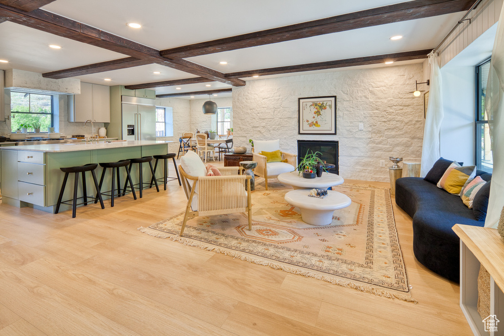 Interior space featuring light wood-style floors, a stone fireplace, recessed lighting, and beam ceiling