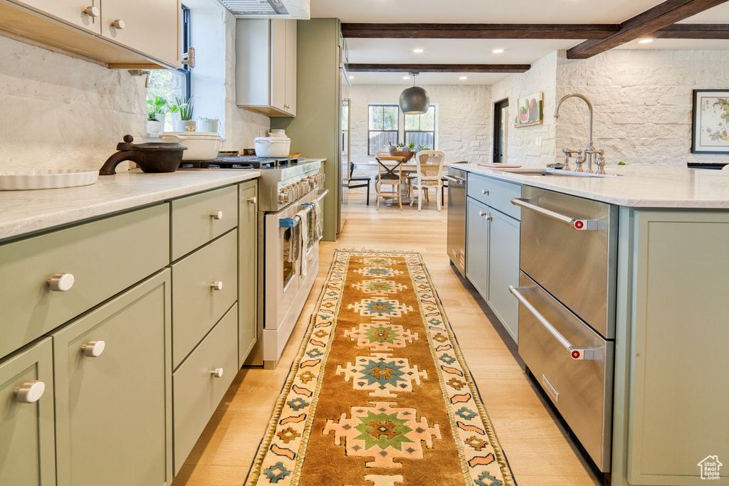 Kitchen featuring green cabinetry, appliances with stainless steel finishes, a sink, and light wood-type flooring