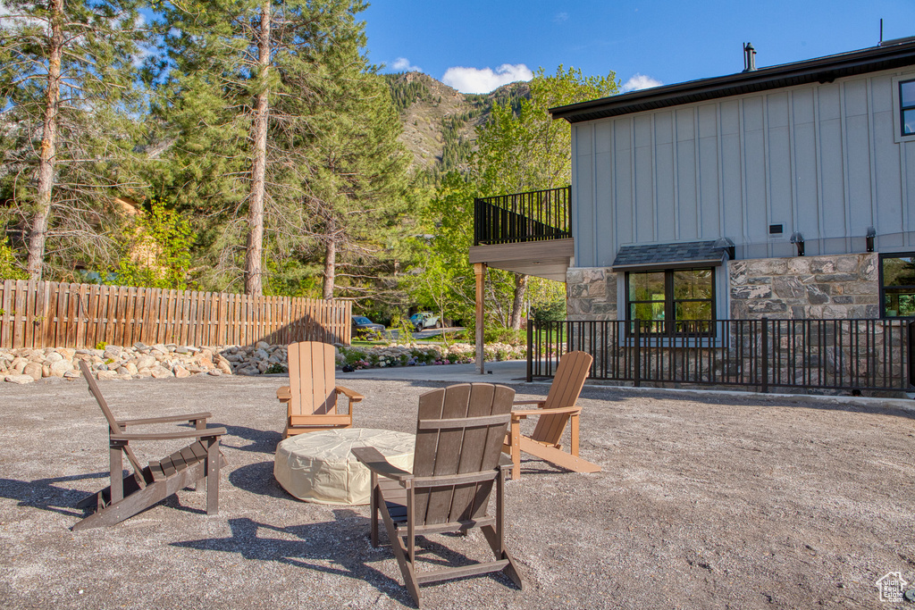 View of patio with fence, a fire pit, and a mountain view