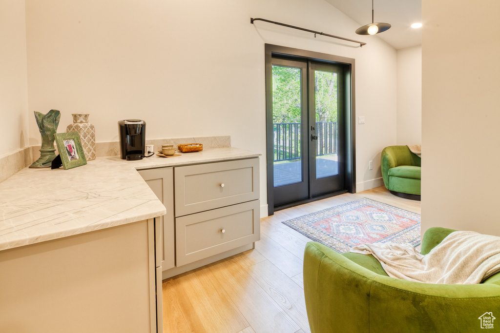 Doorway to outside with vaulted ceiling, french doors, and light wood-style flooring