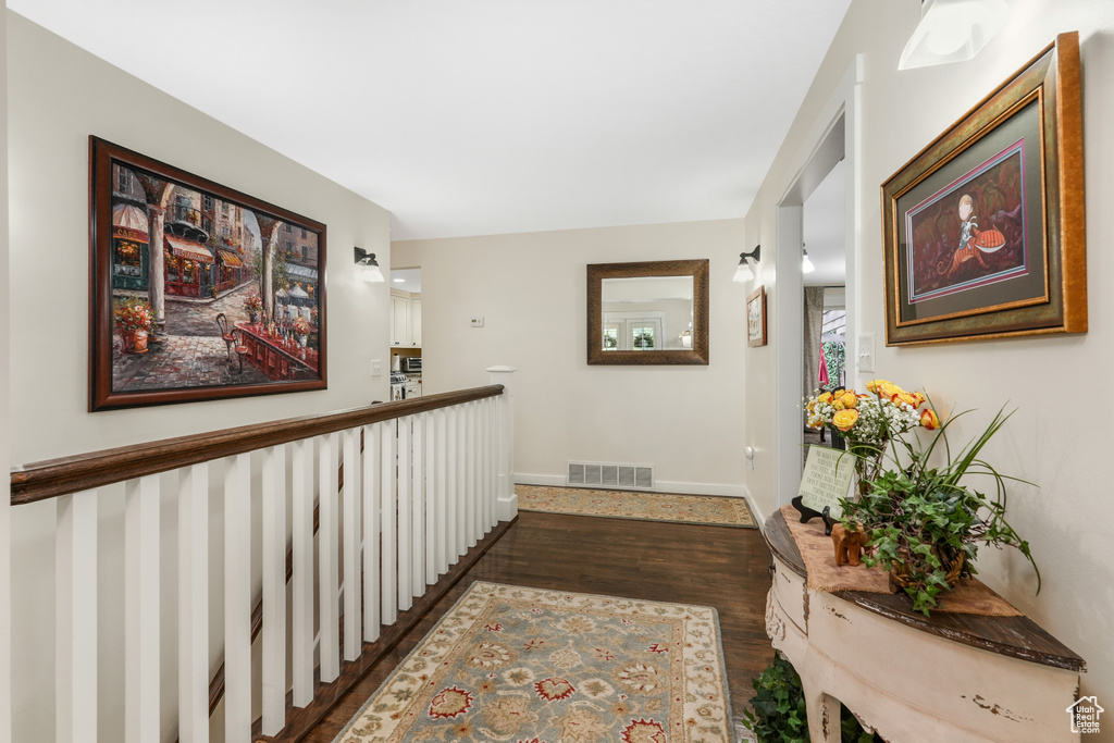 Hall with baseboards, visible vents, and dark wood-style floors