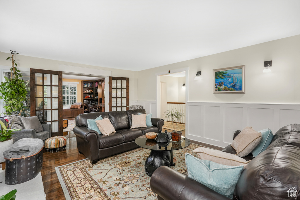 Living area with a wainscoted wall, french doors, wood finished floors, and a decorative wall