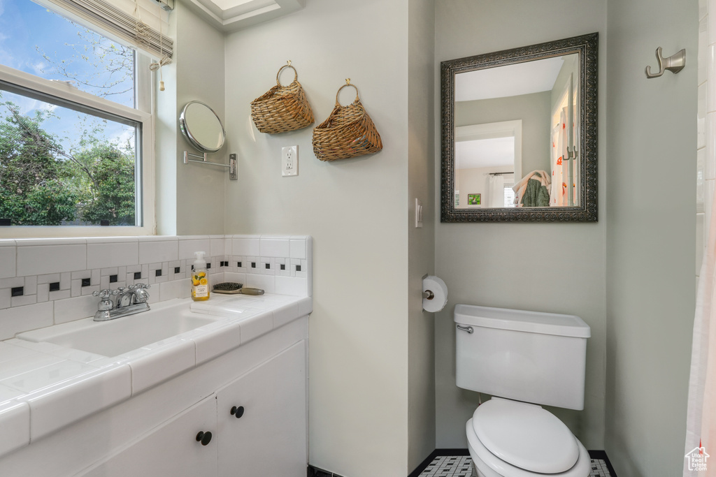 Bathroom with vanity, backsplash, and toilet