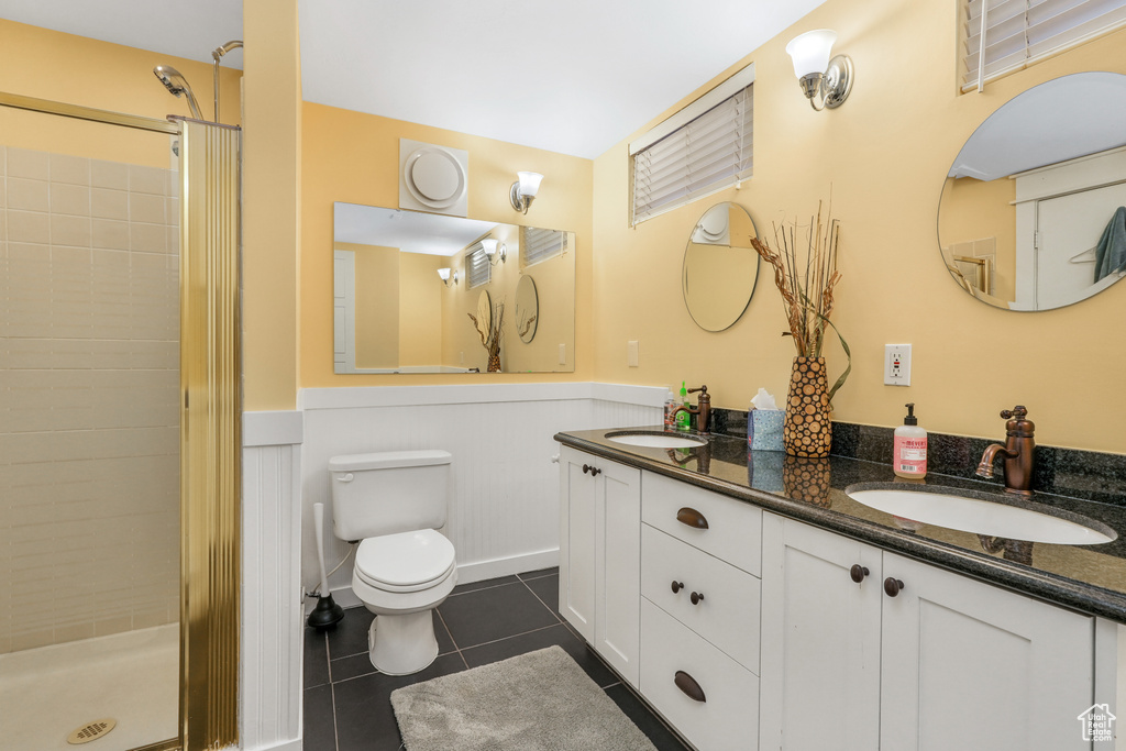 Bathroom featuring a sink, a stall shower, tile patterned floors, and a wainscoted wall