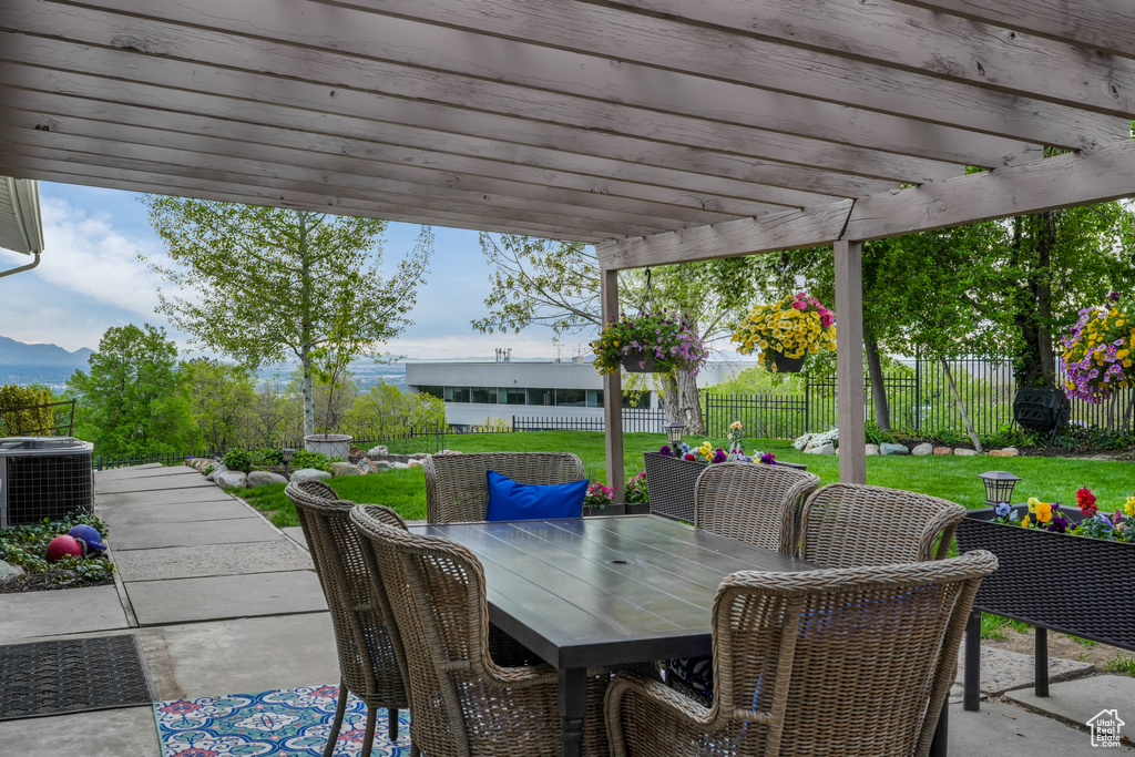 View of patio featuring cooling unit, a mountain view, a fenced backyard, a pergola, and outdoor dining space