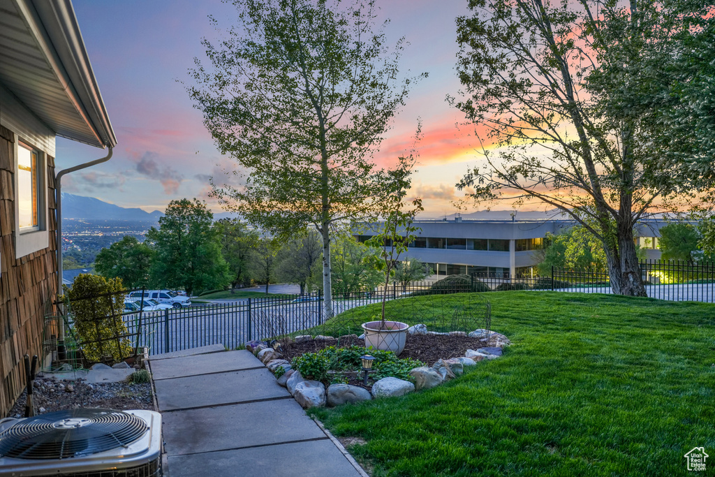Yard at dusk featuring fence and cooling unit