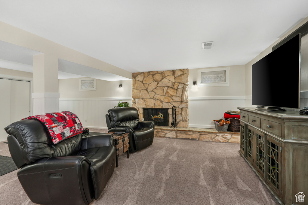 Living room with carpet flooring, visible vents, wainscoting, and a fireplace