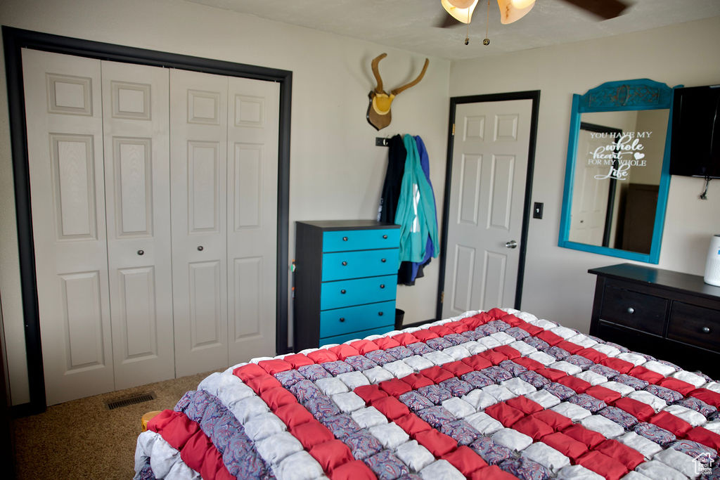 Carpeted bedroom featuring a ceiling fan, visible vents, and a closet