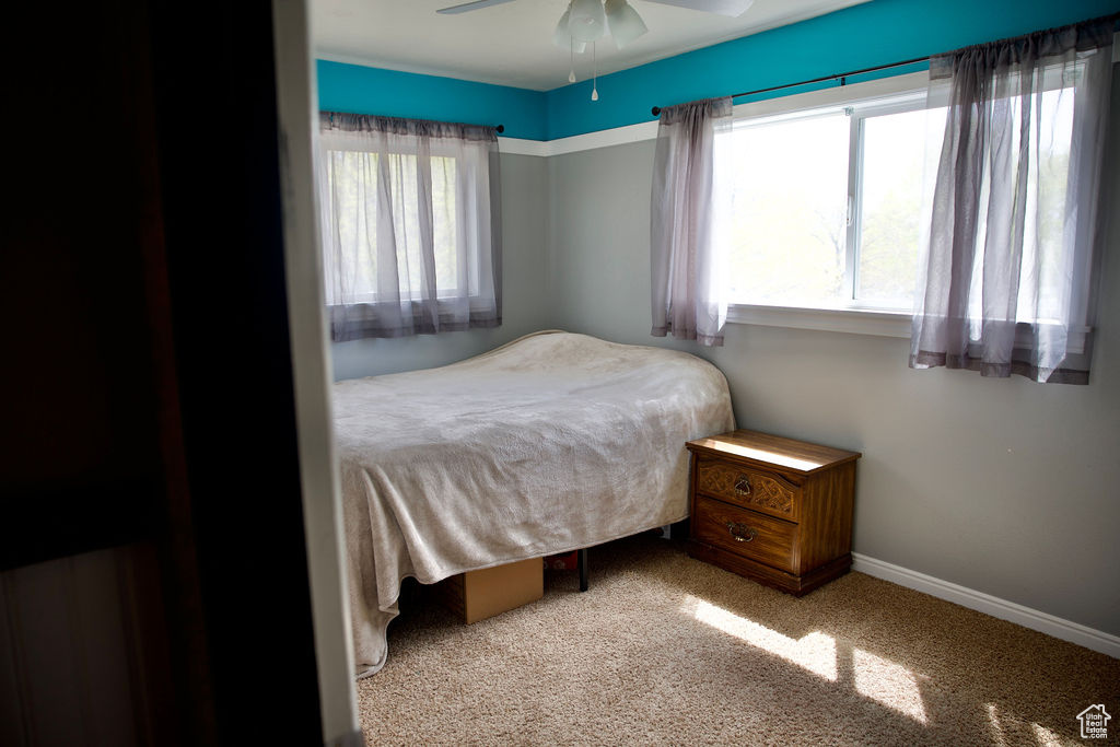 Carpeted bedroom featuring baseboards and ceiling fan