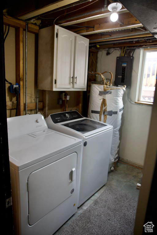 Clothes washing area featuring washer and clothes dryer, cabinet space, water heater, and electric panel