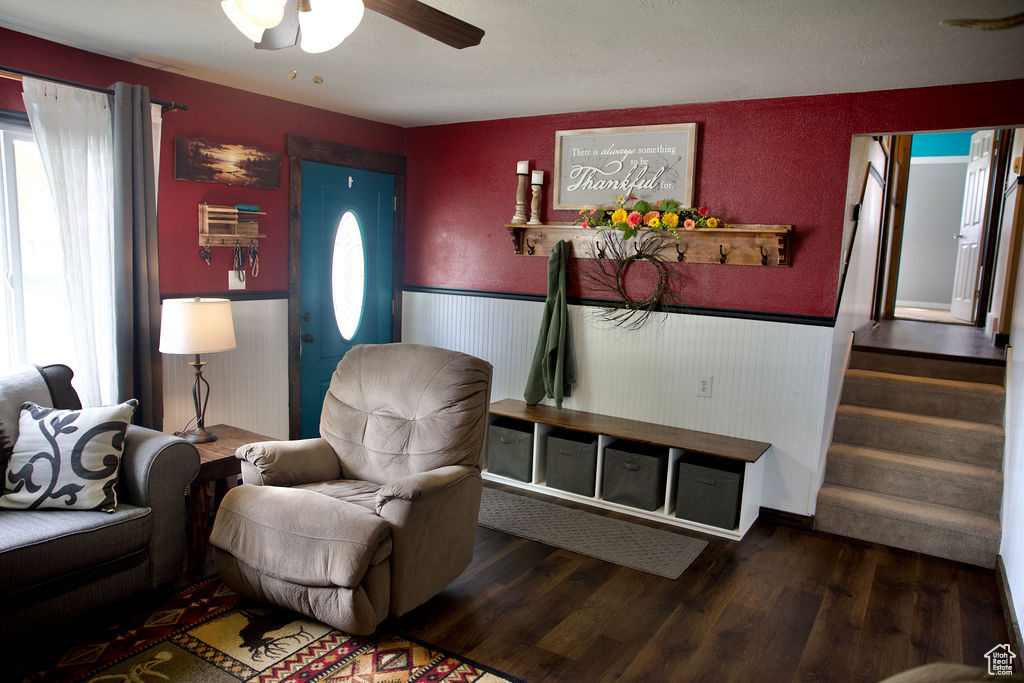 Living room featuring stairway, a wainscoted wall, a ceiling fan, and wood finished floors