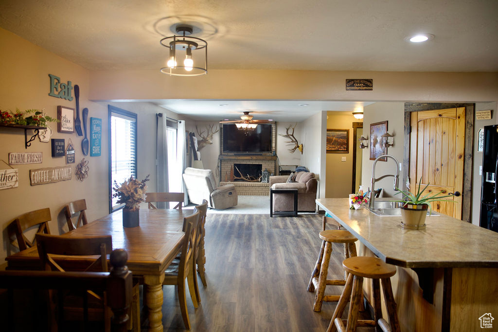 Dining area with a brick fireplace, recessed lighting, ceiling fan, and dark wood finished floors
