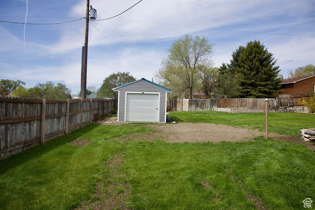 View of yard with a fenced backyard, a storage unit, and an outdoor structure