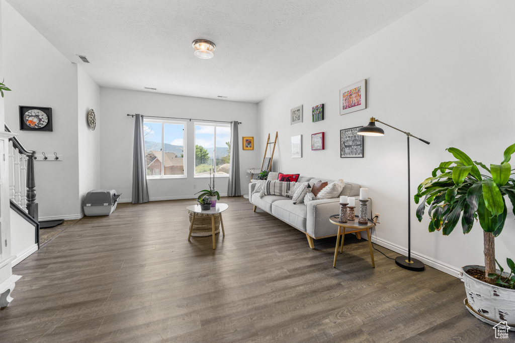 Living area with baseboards, visible vents, wood finished floors, and stairway