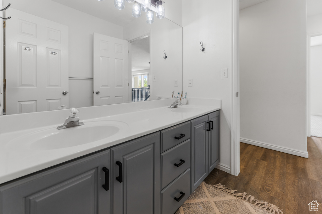 Bathroom featuring double vanity, baseboards, a sink, and wood finished floors