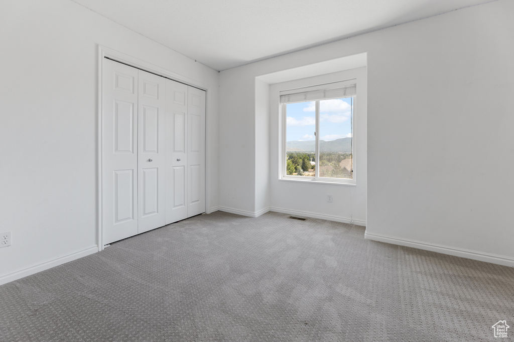 Unfurnished bedroom with carpet floors, baseboards, a closet, and visible vents