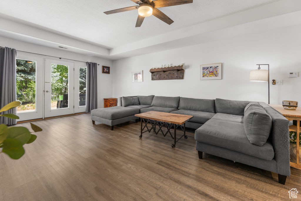 Living area featuring ceiling fan, wood finished floors, and a tray ceiling