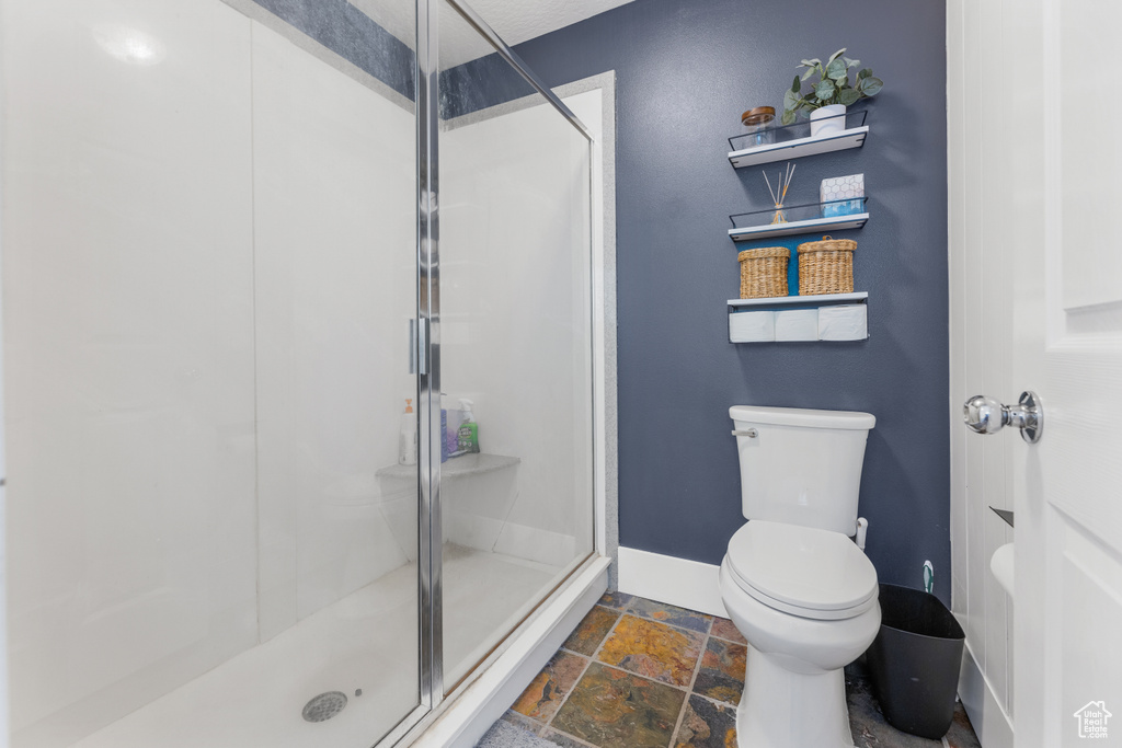 Bathroom with baseboards, a stall shower, and stone tile flooring