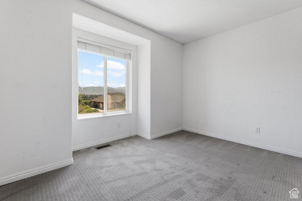Carpeted empty room with baseboards and visible vents