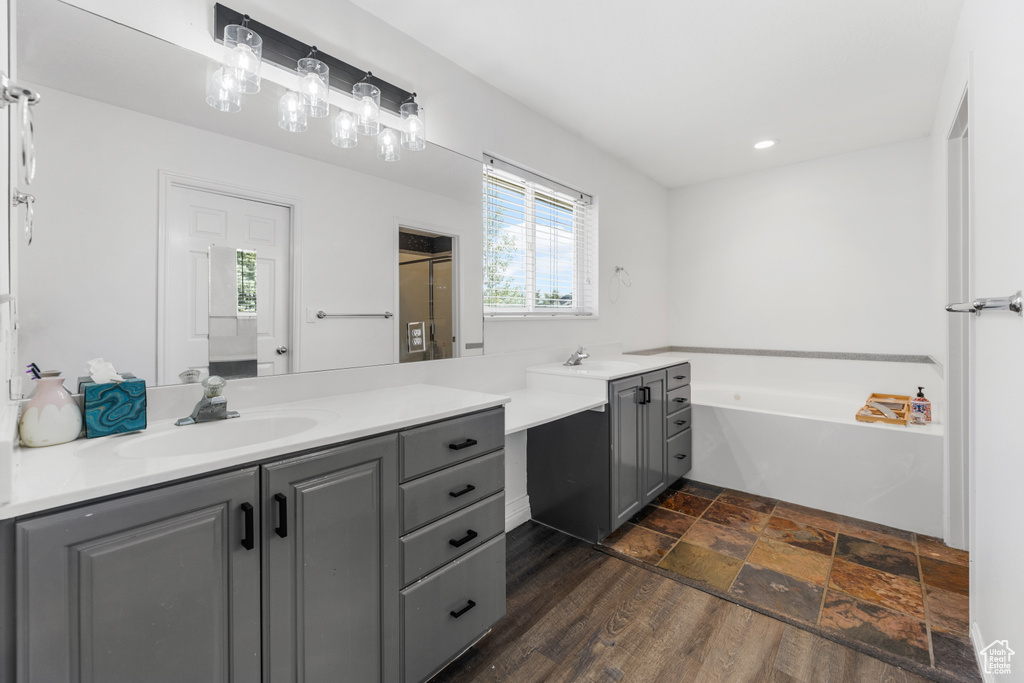Bathroom with a sink, stone finish floor, recessed lighting, two vanities, and a garden tub
