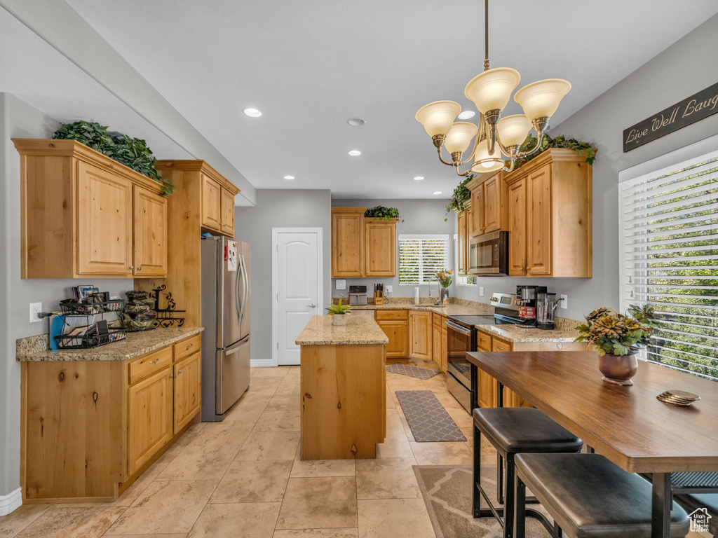 Kitchen with appliances with stainless steel finishes, an inviting chandelier, a center island, recessed lighting, and pendant lighting